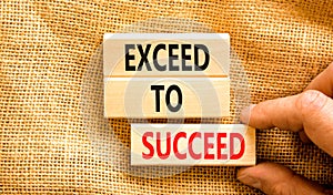 Exceed to succeed symbol. Concept words Exceed to succeed on beautiful wooden blocks. Beautiful canvas table canvas background.