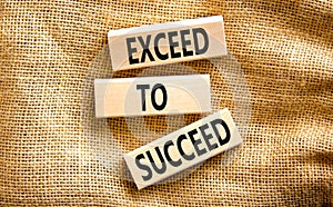 Exceed to succeed symbol. Concept words Exceed to succeed on beautiful wooden blocks. Beautiful canvas table canvas background.