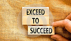 Exceed to succeed symbol. Concept words Exceed to succeed on beautiful wooden blocks. Beautiful canvas table canvas background.