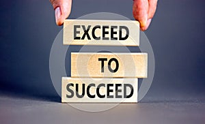 Exceed to succeed symbol. Concept words Exceed to succeed on beautiful wooden blocks. Beautiful grey table grey background.