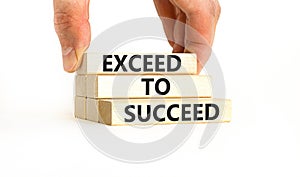 Exceed to succeed symbol. Concept words Exceed to succeed on beautiful wooden blocks. Beautiful white table white background.