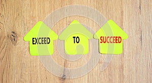 Exceed to succeed symbol. Concept words Exceed to succeed on beautiful yellow paper houses. Beautiful wooden table wooden