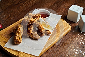 An excellent beer snack is a set of chicken nuggets fries with parchment sauce on a stone tray. Pub food. Close up