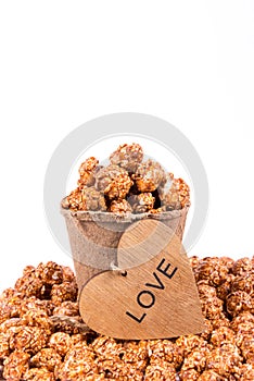 Excellent caramel popcorn in paper cup and wooden heart. Romantic concept.