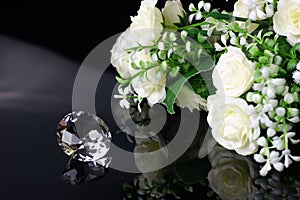 Excellent diamond of the first water and bouquet of white roses with reflection on black mirror background close up view. Jewelry