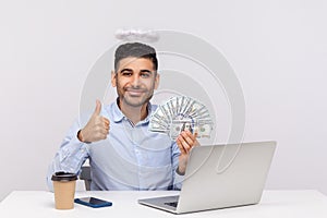 Excellent online earnings! Angelic businessman with nimbus holding dollars and showing thumbs up
