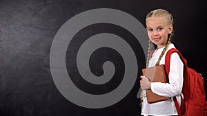 Excellent pupil with book and rucksack standing by blackboard statistic template