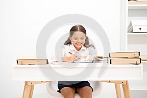 Excellent pupil. Girl child writes hometask while sit table white background. Schoolgirl studying writing essay. Kid photo