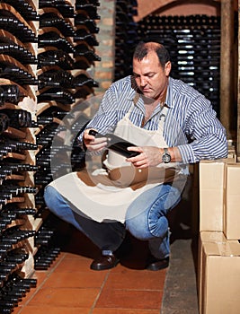 This is an excellent vintage. A mature wine maker counting the bottles of wine in his cellar.