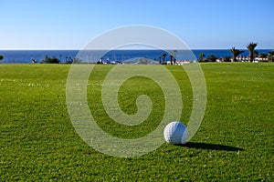 Excellent well-kept green grass lawn on large golf course, green section with big white foam balls for beginners on Tenerife