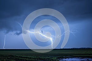 Exceptionally bright lightning strikes earth during a severe nighttime thunderstorm