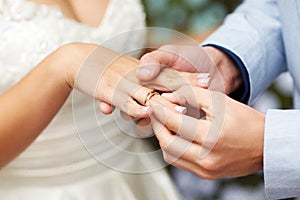 Exchange Of Wedding Rings. Wedding ceremony. Groom puts on golden wedding ring to bridal`s finger, closeup. Bride and groom