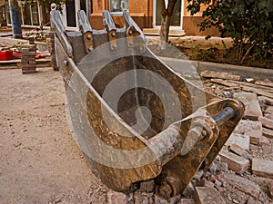 Exchangeable excavator bucket lying on ground of construction site