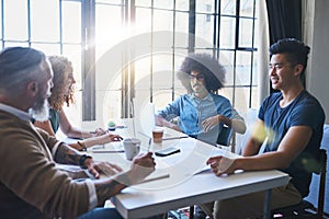 Exchanging ideas. Shot of a group of cheerful creative businesspeople having a meeting around a table together inside