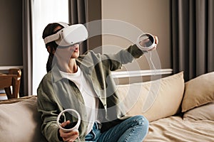 Excite white woman playing online game with vr glasses and controllers