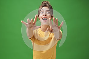 Excited and addicted goog-looking young woman reaching hands forward to camera with reckless look wanting grab something