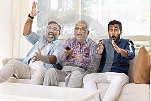 Excited adult Indian men of three generations watching sport match