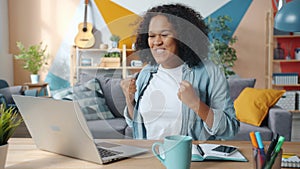 Excited African American business lady enjoying success at freelance work at home