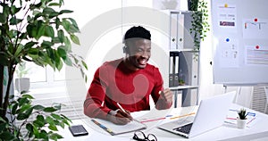 Excited African American businessman listening music and working on laptop