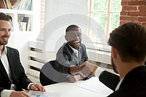 Excited african american businessman shaking partner hand after