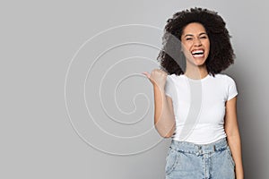 Excited African American girl laughing, pointing aside to copy space