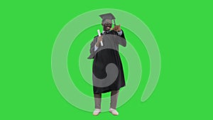 Excited african american male student in graduation robe waiving his diploma and posing for camera on a Green Screen