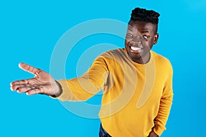 Excited african american man outstretching hand, holding invisible object on his palm