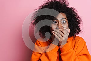 Excited african american woman covering her mouth and looking at camera