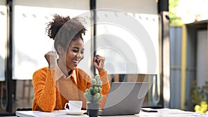 Excited African American woman reading email with good news on laptop, motivated by great offer or new opportunity