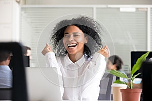 Excited African American woman receiving good news on laptop