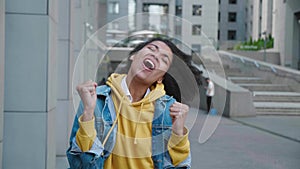 Excited african american young woman in jean jacket making winner gesture with two hands and screaming celebrating