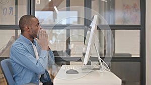 Excited African Businessman Celebrating Success on Desktop in Office