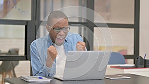 Excited African Businessman Celebrating Success on Laptop in Office