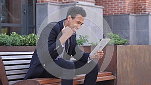 Excited African Businessman Celebrating Success on tablet Sitting on Bench