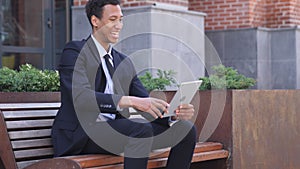 Excited African Businessman Celebrating Success on tablet Sitting on Bench