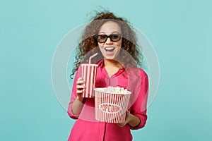 Excited african girl in 3d imax glasses watching movie film hold popcorn cup of soda isolated on blue turquoise