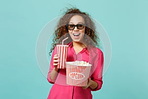 Excited african girl in 3d imax glasses watching movie film hold popcorn cup of soda isolated on blue turquoise photo
