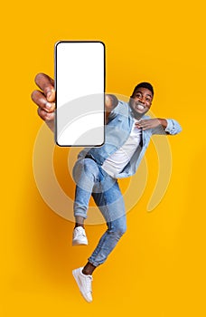 Excited african guy dancing with modern smartphone photo