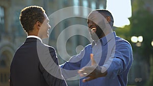 Excited african man feeling proud of young son in prom suit, college graduation