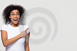 Excited african woman looking up aside pointing finger at copyspace