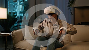 Excited African woman playing virtual reality game at home night happy American girl in gaming simulation VR helmet