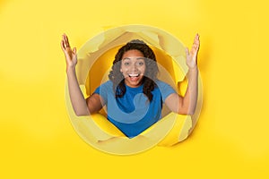 Excited African Woman Posing In Torn Paper On Yellow Background