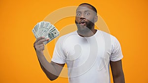 Excited Afro-American man holding bunch of dollar, crowdfunding or start-up