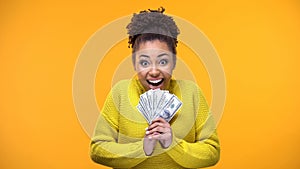 Excited Afro-American woman holding bunch of dollars, lottery winner, fortune