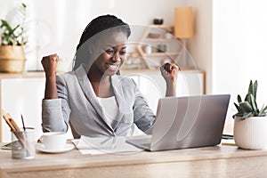 Excited Afro Businesswoman Celebrating Success At Workplace In Modern Office