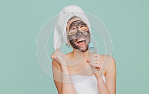 Excited amazed beautiful woman with cosmetic mud facial procedure, spa health concept. Skin care beauty treatment. Towel