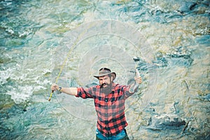 Excited amazed fisher man in water catching trout fish, top view. Fisherman man on river or lake with fishing rod.