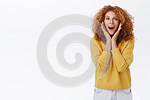 Excited, amused good-looking caucasian redhead woman with curly hair, look wondered and astonished, gasping fascinated