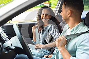 Excited arab couple fastening seat belt, going vacation by car