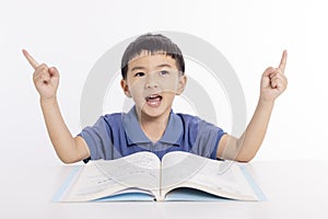 Excited asian child schoolboy studying at home and hand pointing up